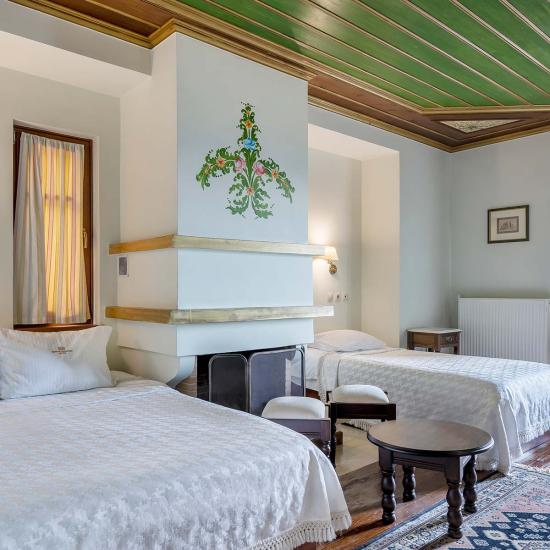 Room with 1 double bed, 1 single bed and a fireplace.